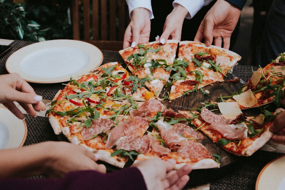 Mani che prendono fette di pizza da condividere